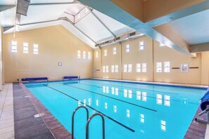 Une piscine intérieure avec des couloirs bien délimités, un plongeoir et un sol carrelé.