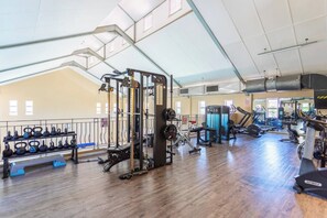 Une salle de sport équipée de divers appareils d’entraînement, notamment des kettlebells, un support à squats et des appareils de cardio.
