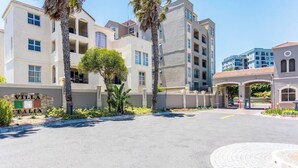 Un edificio residenziale a più piani con un'area ingresso pavimentata, palme e un cartello che recita 'Villa Italia'.