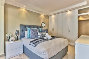 A bedroom with a bed, nightstands, a dresser, and built-in wardrobes.