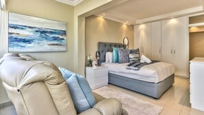 A bedroom with a bed, nightstands, a chair, and a wardrobe. - Stylish 1BR Sea View Apartment near V&A by CTHA (Cape Town)