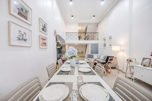 A dining area with a long table set for four, surrounded by chairs, with a staircase leading to an upper level. - Bangkok Group Haven - 6BR Bangchak BTS 12 sleeps (Bangkok)