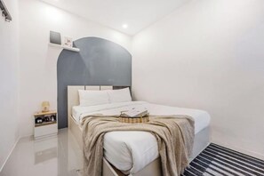 A bedroom with a bed, bedside table, and a small shelf. - Bangkok Group Haven - 6BR Bangchak BTS 12 sleeps (Bangkok)