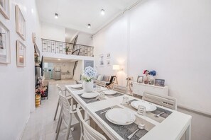 Ein Essbereich mit einem langen Tisch, Stühlen und einer Treppe, die zu einer oberen Ebene führt.