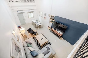 A high-ceilinged living area with a sofa, a coffee table, and a television. - Bangkok Group Haven - 6BR Bangchak BTS 12 sleeps (Bangkok)