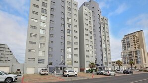 A multi-story residential building with a modern architectural design, featuring balconies and a central stairwell. - 3br Beach Stay | Views & backup power by ctha (Cape Town)