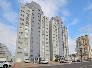 Un edificio residenziale a più piani dal design architettonico moderno, con balconi e una scala centrale.