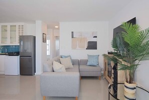 A modern living room with a grey sofa, a small table, and a potted plant.