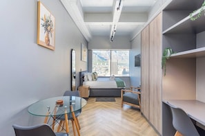 Una camera moderna con un tavolo in vetro, un letto e una vista sulla città, e un'ampia finestra.