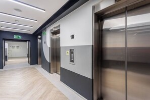 A modern elevator with a metallic finish, a floor number sign, and a door with a handle.