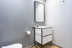 Un bagno con un WC bianco, un lavabo con cornice nera e uno specchio sopra il lavabo.