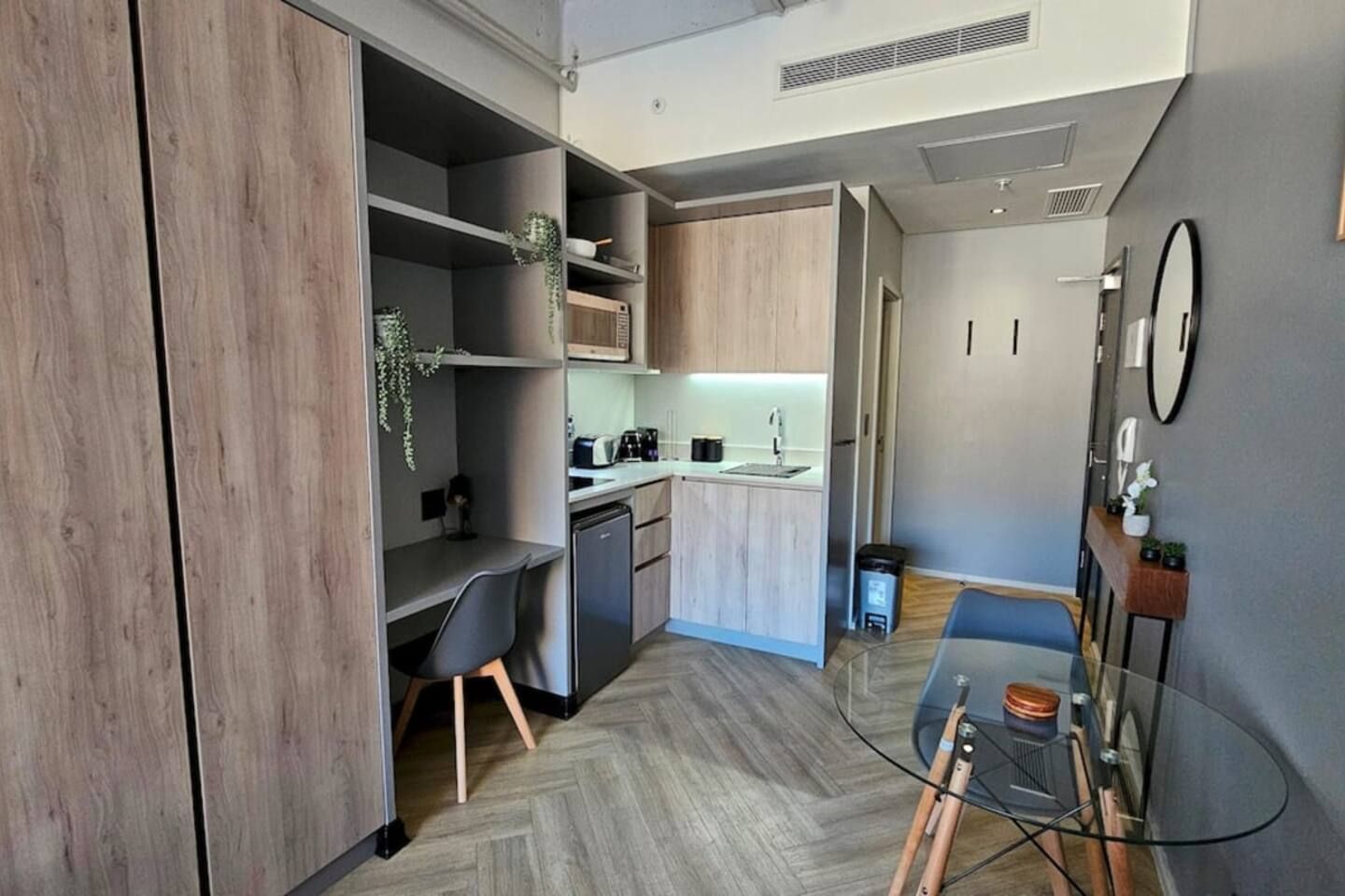 A compact kitchen with modern appliances, a dining area with a glass table, and a small seating space.
