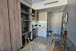 A compact kitchen with modern appliances, a dining area with a glass table, and a small seating space.