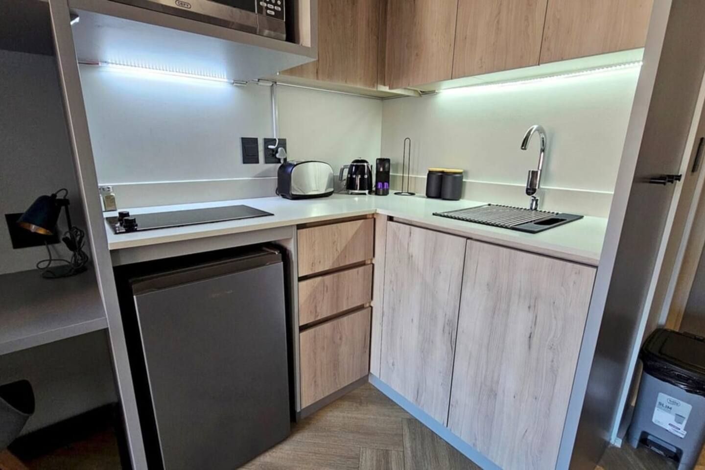 A compact kitchen with a built-in dishwasher, a coffee maker, and a sink.