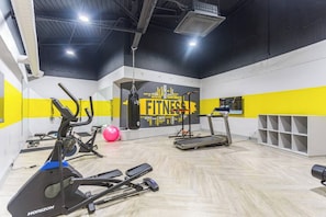 A gym with exercise equipment, a punching bag, and a wall with motivational words.