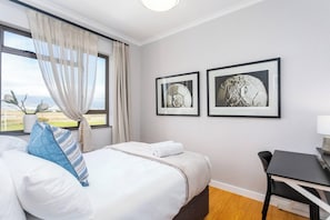 Una camera d'albergo con un letto, una scrivania e due quadri appesi al muro.