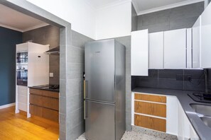 A modern kitchen with a stainless steel refrigerator, wooden cabinets, and a built-in oven.