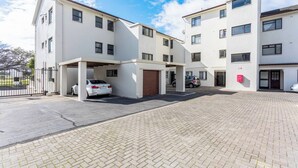 A multi-story residential building with a covered parking area and a paved walkway. - Burmeister Circle by Ctha (Milnerton)