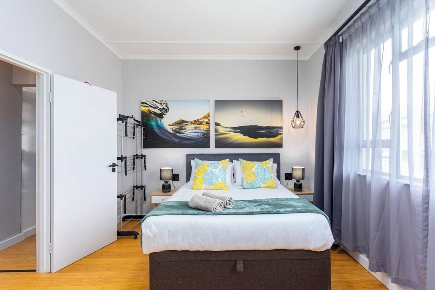 A modern bedroom with a bed, two bedside tables, a wardrobe, and artwork on the wall.
