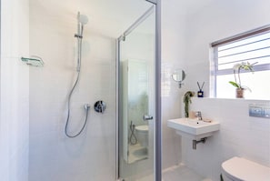 Un bagno moderno con doccia vetro, lavandino bianco e water.