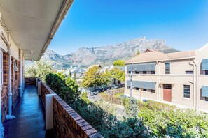 A balcony with a view of a mountain and residential buildings.