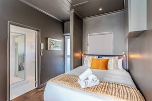 Una camera d'albergo con un letto, un quadro e una porta che dà su un bagno.