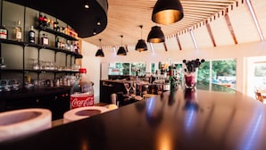 A bar area with shelves of liquor bottles, a Coca-Cola bottle, and bar tools on the counter. - Club Vacances Bleues Le Grand Air (Saint-Trojan-les-Bains)