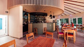 A restaurant with wooden furniture, a bar area, and large windows. - Club Vacances Bleues Le Grand Air (Saint-Trojan-les-Bains)