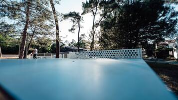 Een skatepark met een houten omheining, bomen en een huis op de achtergrond.