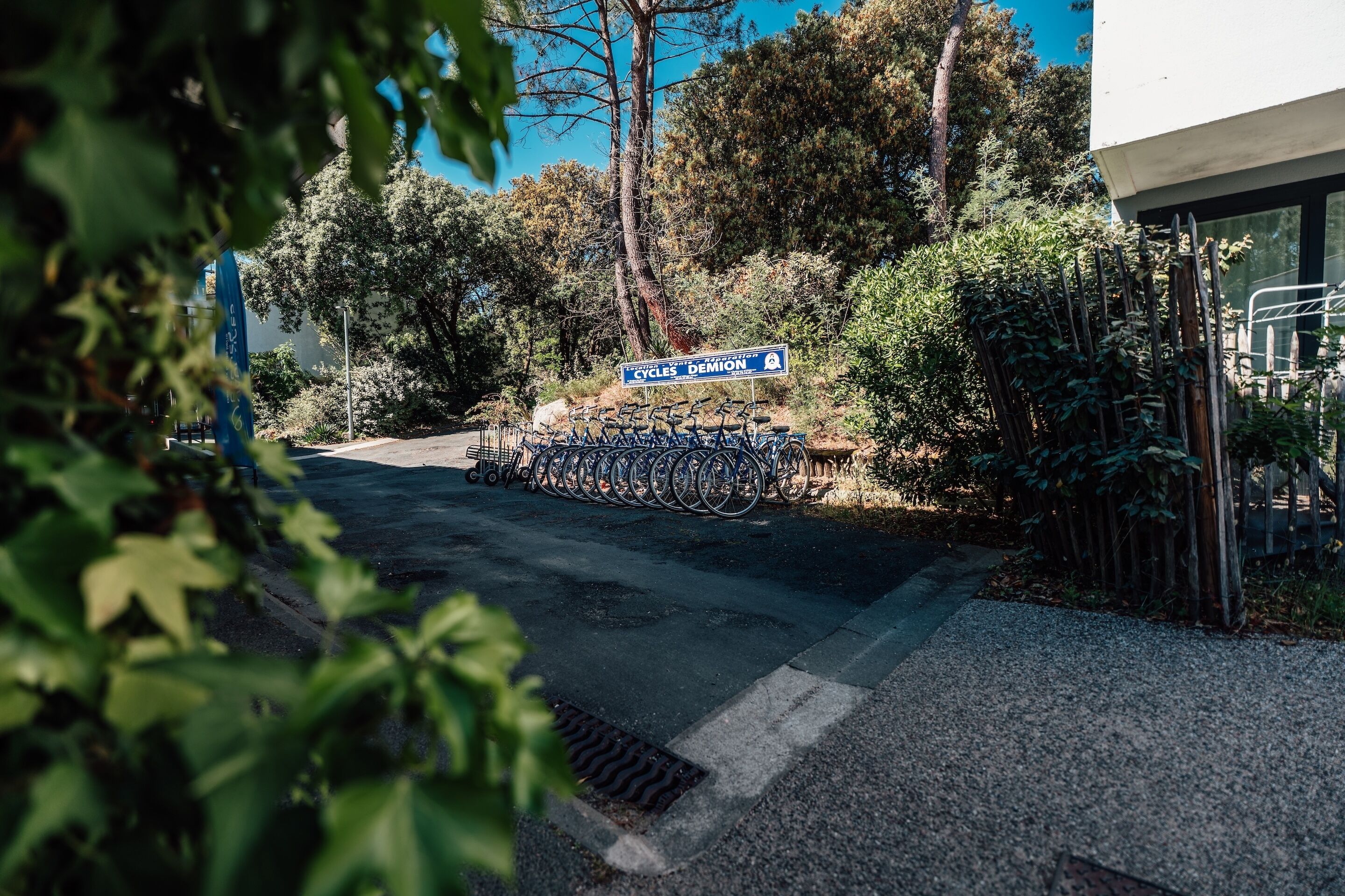 A parking area with bicycles, a sign for 'Cycles Demon,' and a building with a modern design.