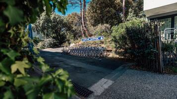Un espace de stationnement avec des vélos, un panneau indiquant « Cycles Demon », et un bâtiment à l’architecture moderne.