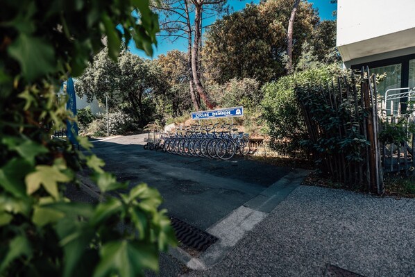 Un aparcamiento con bicicletas, un cartel que indica 'Cycles Demon' y un edificio de diseño moderno.