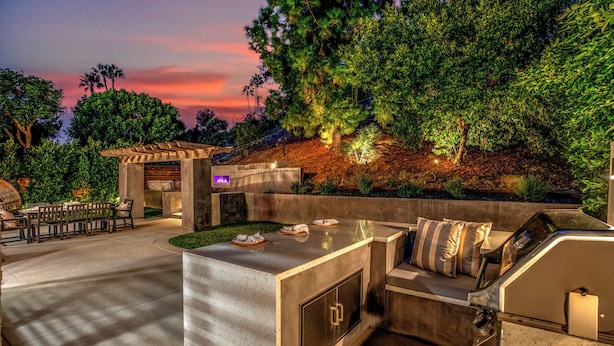 An outdoor kitchen area with a built-in grill, seating, and a fire feature. - Modern SoCal Escape with Outdoor Grill & Lush Lounge Areas | Casa Cordero (Mission Viejo)