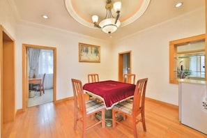 A dining area with a table, chairs, a chandelier, and a painting on the wall.