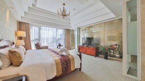Une chambre d’hôtel dotée d’un grand lit, d’une télévision, d’un bureau et d’un coin salon offrant une vue sur la ville.
