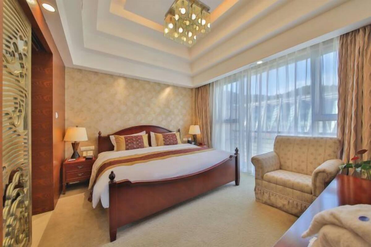 Une chambre d’hôtel avec un grand lit, des lampes de chevet, un fauteuil et une vue sur la ville.