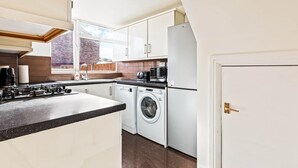 A modern kitchen with a built-in washer and dryer, a microwave, and a coffee maker. - Spacious & Modern 4-Bed Home – Sleeps 7 (Newquay)