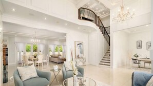 A spacious living area with a round coffee table, sofas, and a staircase leading to an upper floor.