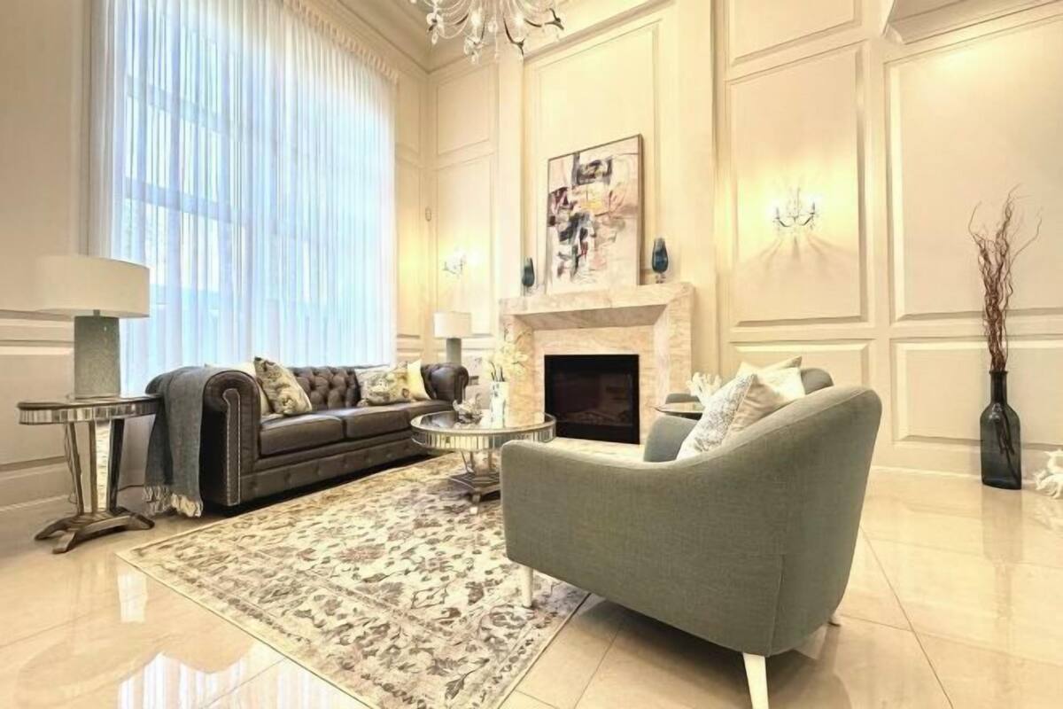 Ein Wohnzimmer mit Kamin, einer Couch, einem Sessel, einem Couchtisch und einem Teppich.