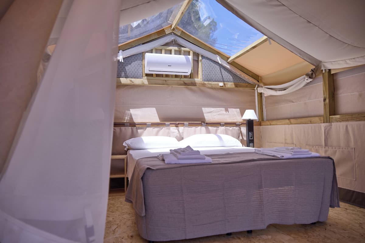 Ein Zeltunterstand mit einem Bett, Kissen und einem Fenster.