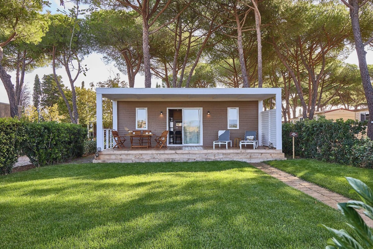 Ein modernes, eingeschossiges Haus mit einer Terrasse, ausgestattet mit einem Esstisch und Stühlen.