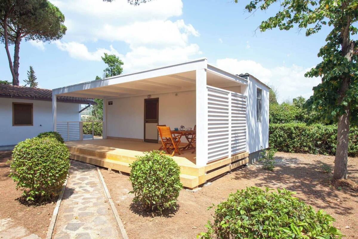 Einbungalow mit überdachter Terrasse, Esstisch und Stühlen.