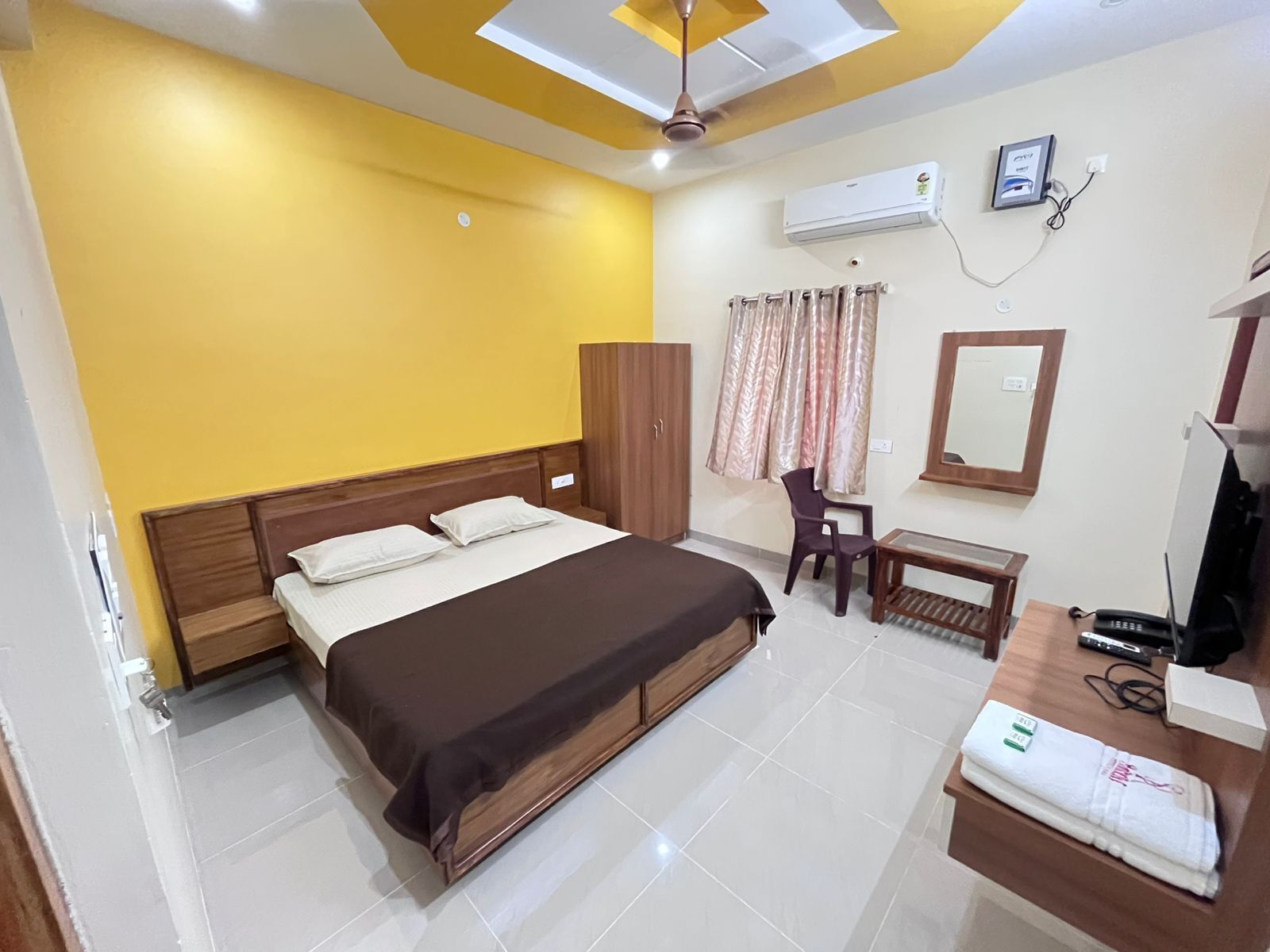 Hotelkamer met een bed, bureau, stoel, kast, airconditioning en een televisie.