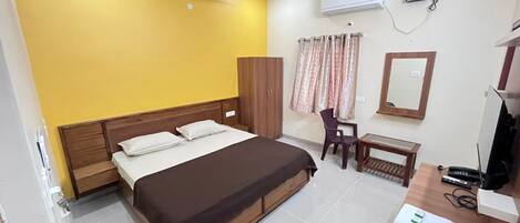 Hotelkamer met een bed, bureau, stoel, kast, airconditioning en een televisie.