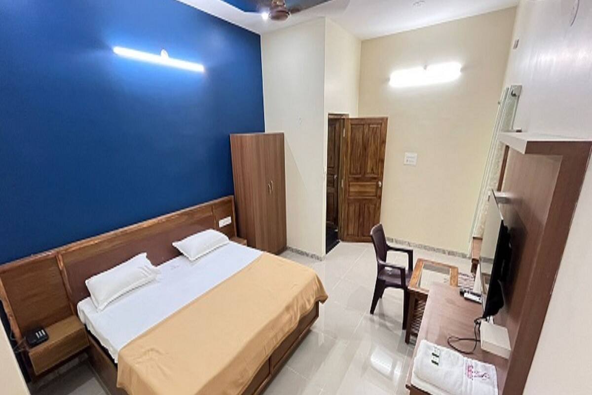 A hotel room with a bed, a desk, a chair, a wardrobe, and a television.