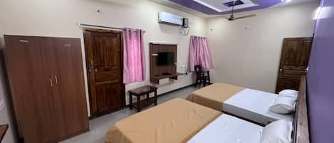 A hotel room with two beds, a wardrobe, a TV, and a ceiling fan.