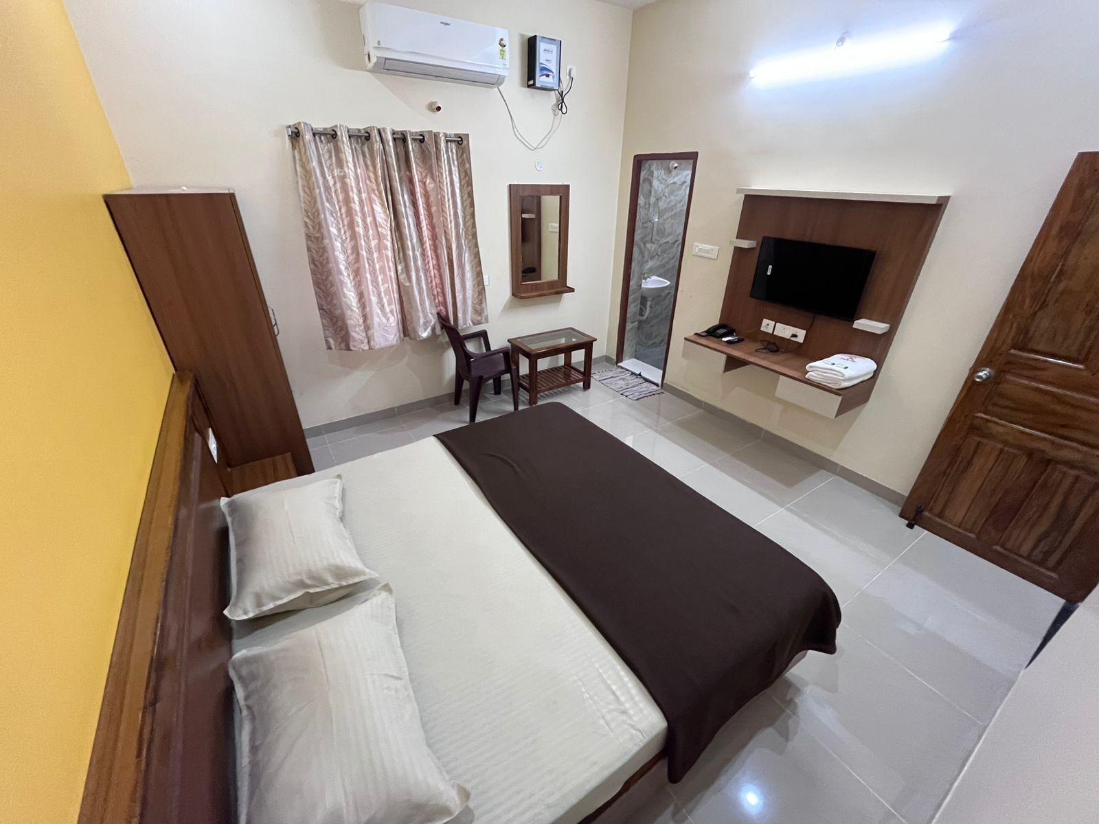 Une chambre d’hôtel comprenant un lit, un bureau, une chaise, une télévision et une armoire.