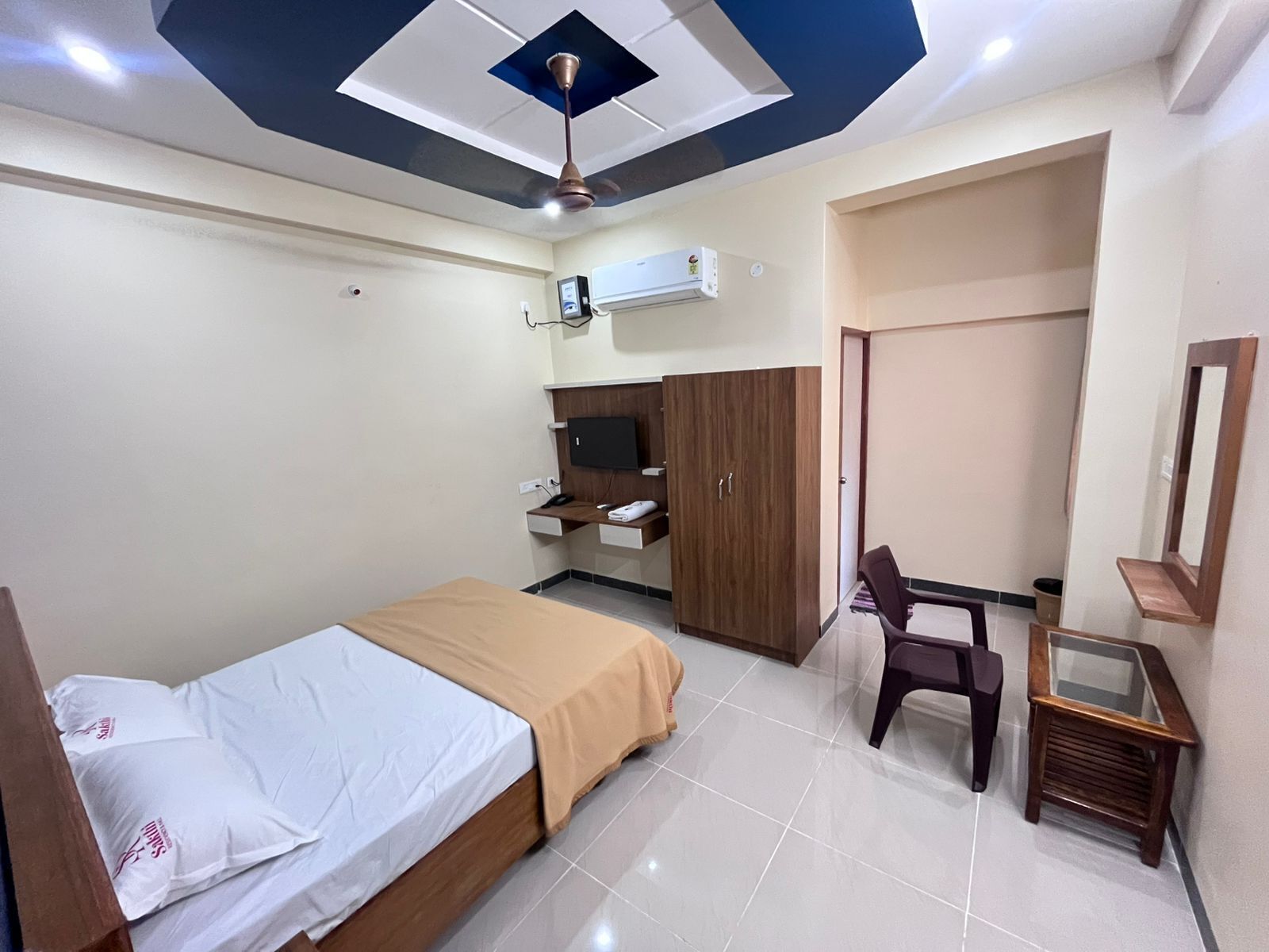 A bedroom with a bed, a desk, a wardrobe, and a ceiling fan.