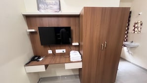 Une chambre dotée d’un bureau en bois, d’un téléviseur à écran plat, d’un téléphone et d’un placard.