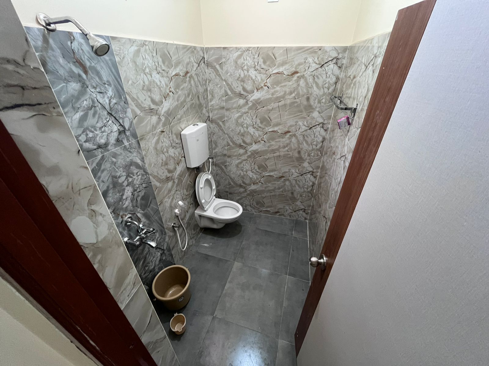 Een badkamer met een marmeren wand, een toilet, een douche en een bidet.